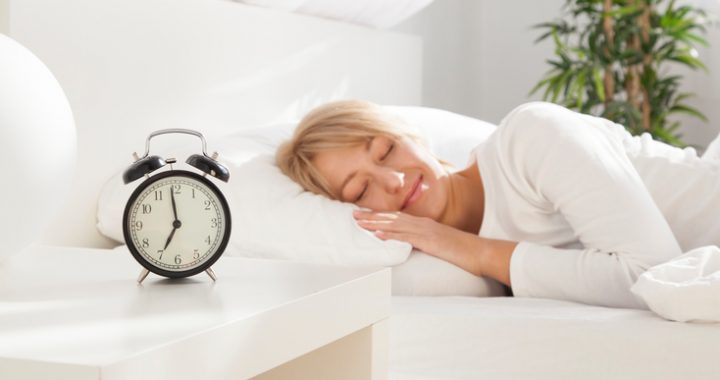 beautiful girl sleeping in her bed.  focus on clock